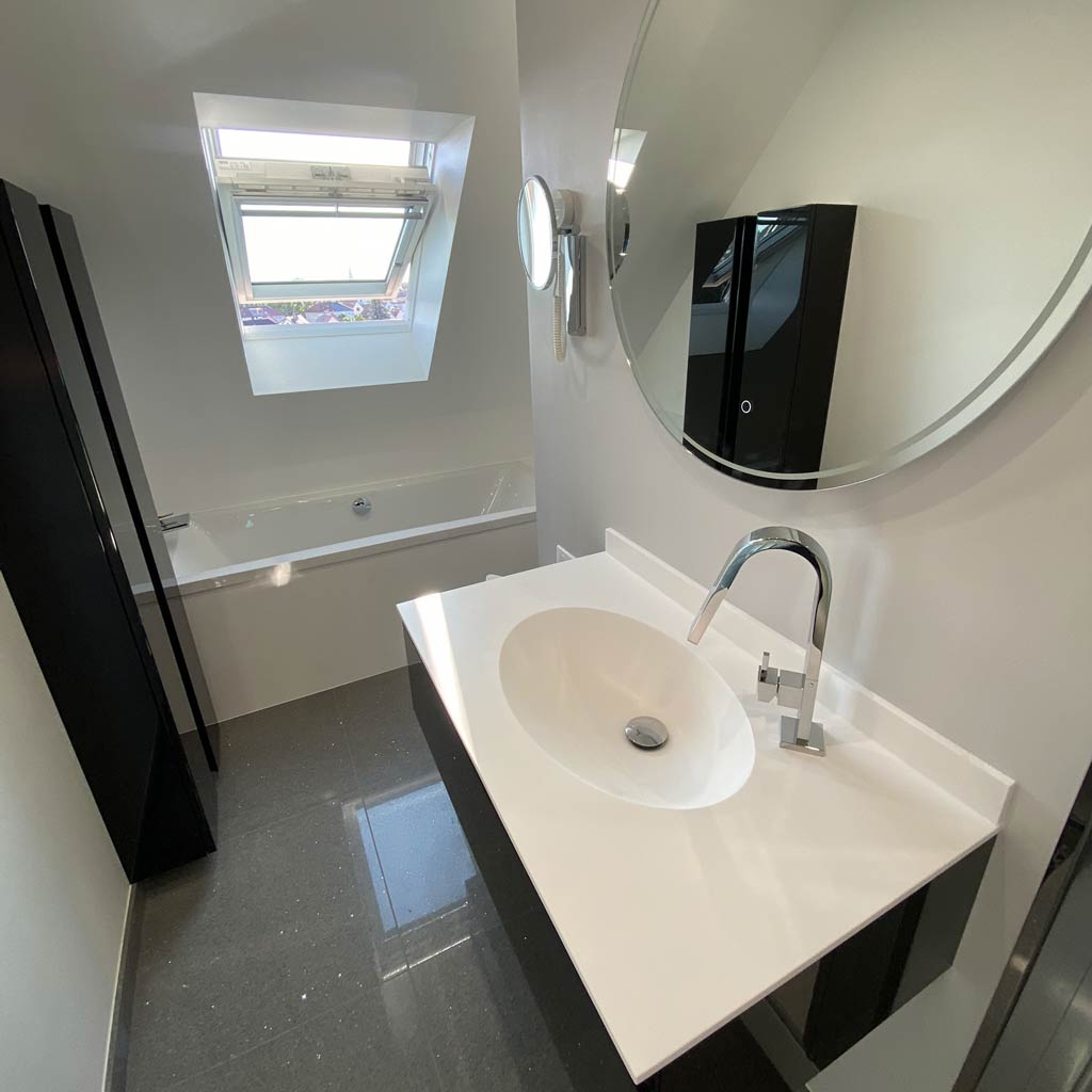 Aménagement salle de bain moderne noir et blanche avec bain, vasque fixé au mur et miroir lumineux