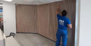 Travaux de pose d'une cloison acoustique design en bois pour la création d'un espace vaccination dans une pharmacie près de Metz