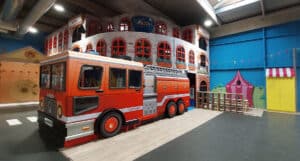 Espace de jeux pour enfants sur 3 niveaux réalisé sur mesure sur le thème des pompiers avec un camion rouge en bois
