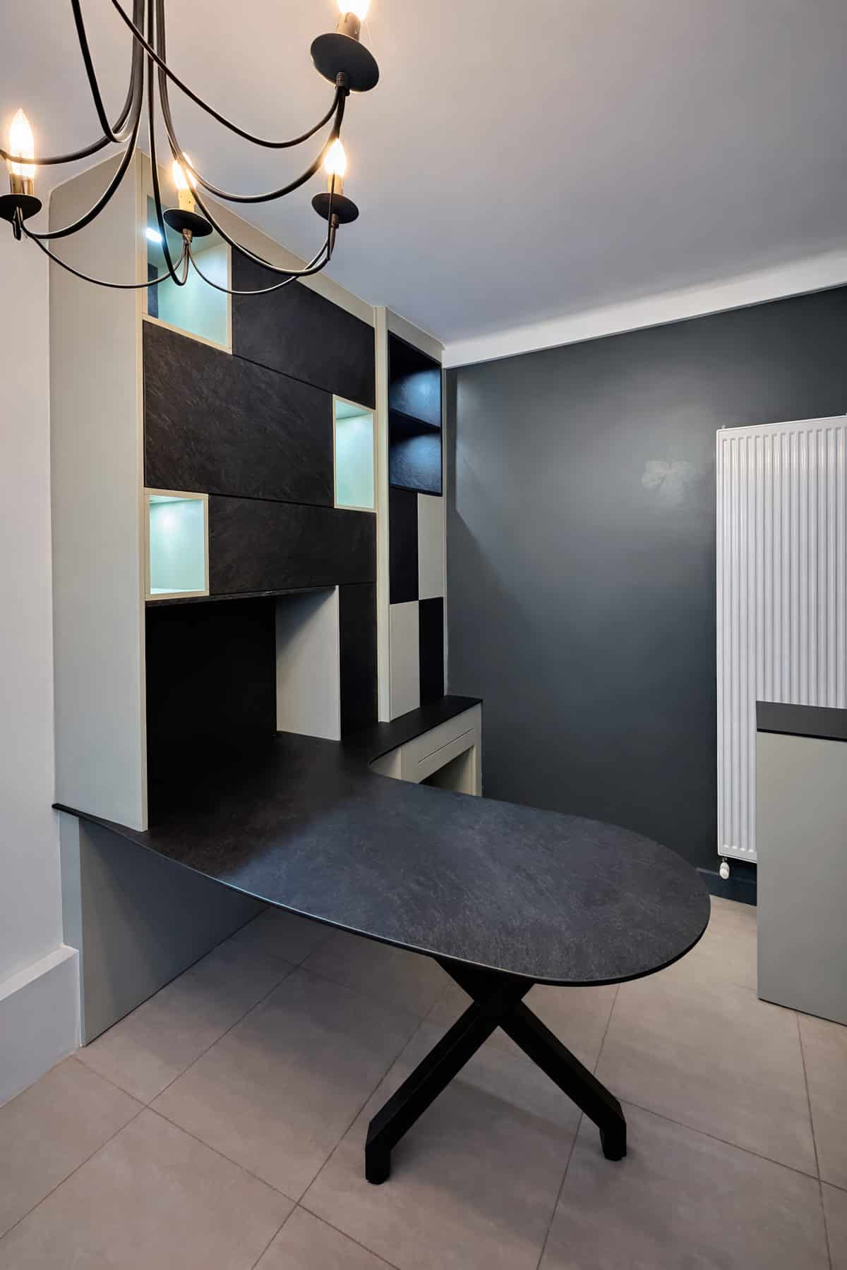 Création d'un bureau design en bois noir avec rangements intégrés. L'aménagement et la décoration des murs et sols sont coordonnés au mobilier.